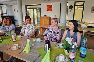 Gruppe von vier Personen bei einem Treffen an einem Tisch mit Getränken und Dekoration.