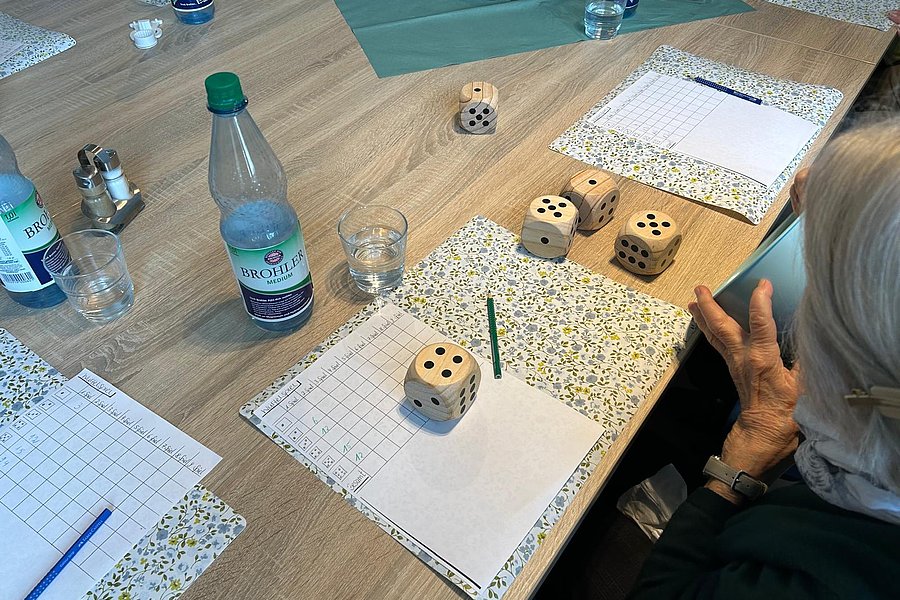 Spielszene mit Holzwürfeln, Zettel und Getränken auf einem Tisch