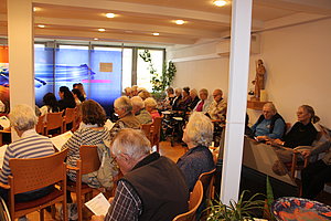 Senioren sitzen gemeinschaftlich in einem Kirchenraum