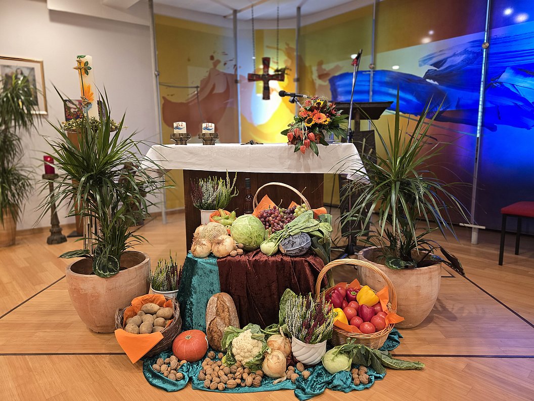 Dekoration mit verschiedenen Obst- und Gemüsesorten, arrangiert um einen Tisch in einem Kirchenraum.