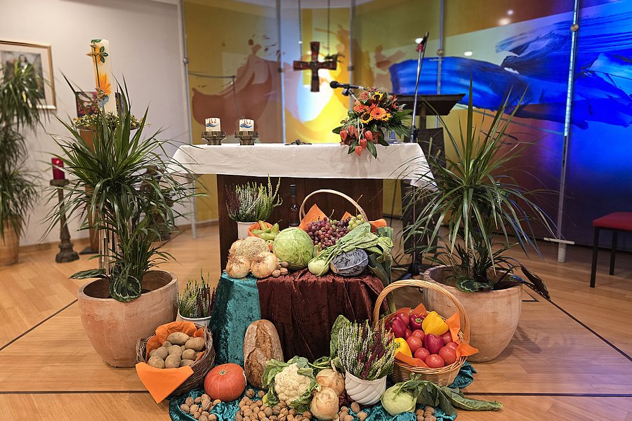 Dekoration mit verschiedenen Obst- und Gemüsesorten, arrangiert um einen Tisch in einem Kirchenraum.