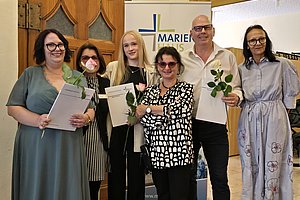 Gruppe von Personen mit Dokumenten und Blumen. Festliche Atmosphäre.