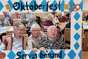 Oktoberfest-Rahmen mit fröhlichen Seniorinnen, die zusammen in einem festlich dekorierten Raum posieren.