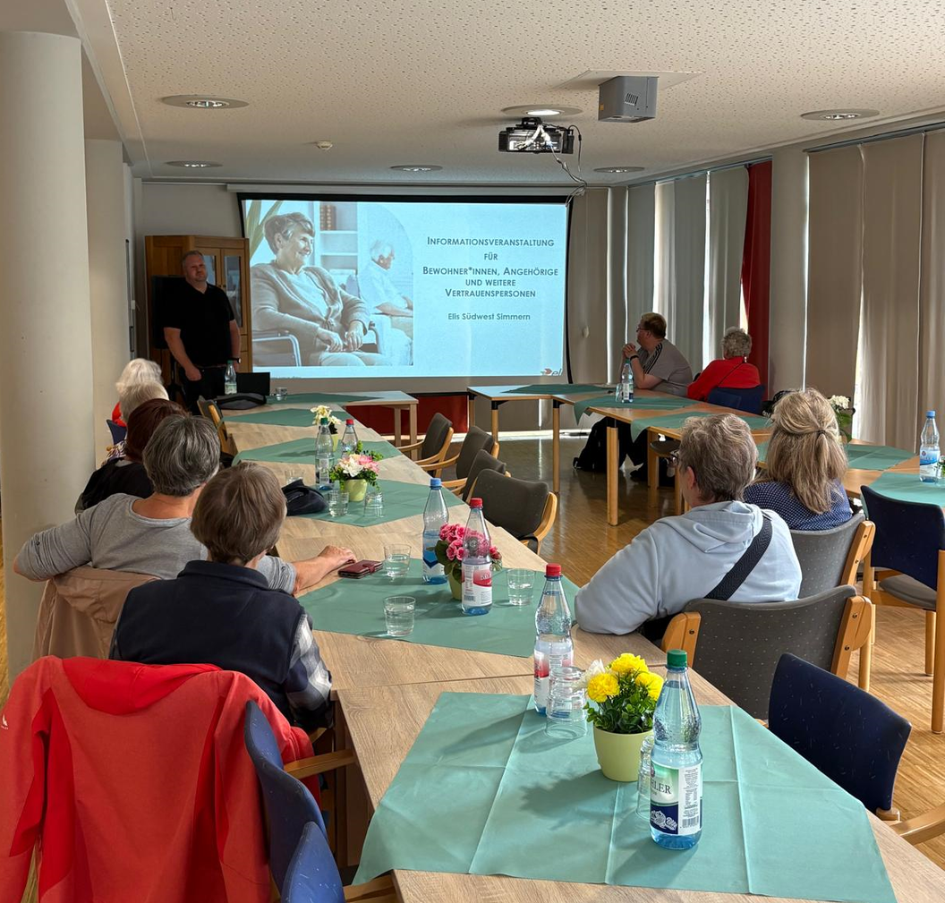 Gruppensitzung mit Präsentation, Tischen dekoriert mit Blumen und Wasserflaschen.