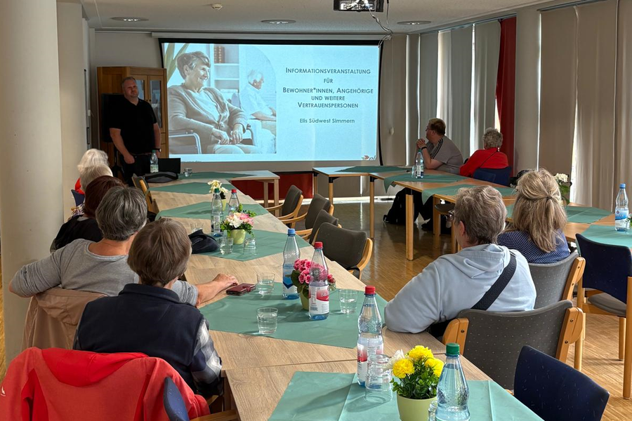 Gruppensitzung mit Präsentation, Tischen dekoriert mit Blumen und Wasserflaschen.