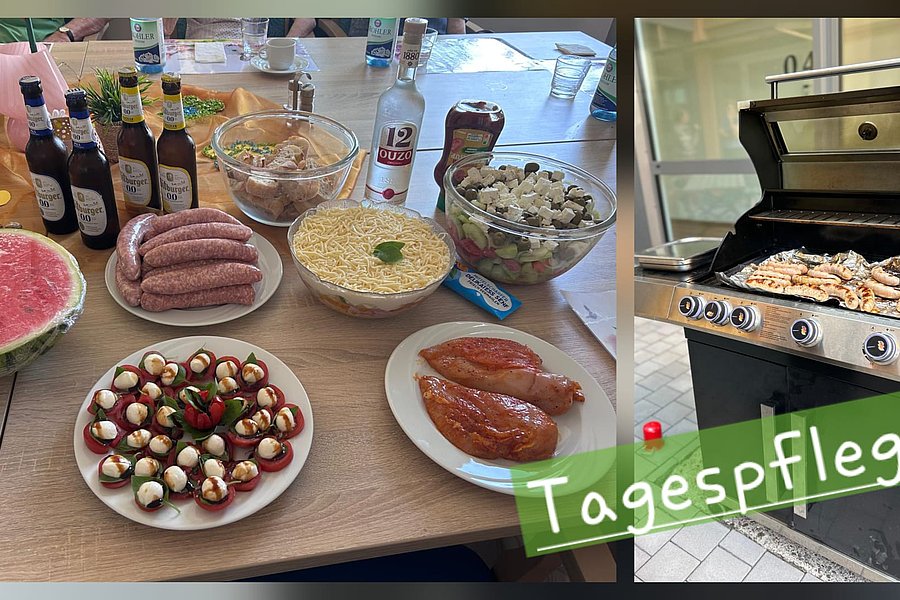 Auf einem Tisch stehen verschiedene Lebensmittel wie Würstchen, Tomaten mit Mozzarella, eine Schüssel mit Nudeln, Flaschen und eine Schale mit Fleisch, daneben ein Grill mit darauf liegendem Grillgut