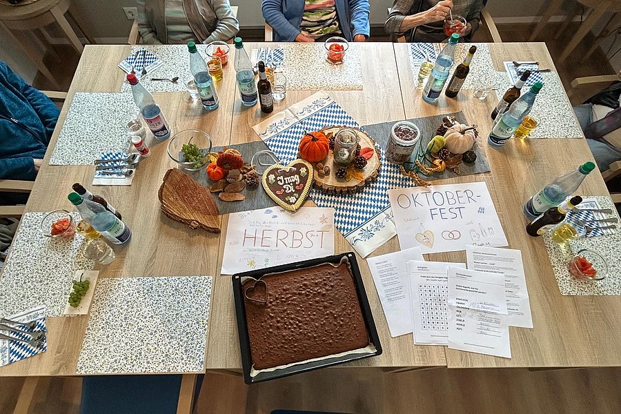 Gemütliche Tafel mit Oktoberfest-Deko, Bierflaschen, Kuchen und herbstlichen Elementen.
