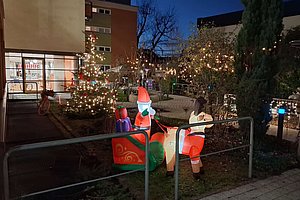 Weihnachtliche Dekoration mit leuchtendem Weihnachtsmann und Schlitten in verschneiter Umgebung.