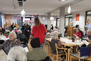 Feiernde Senioren in einem gemütlichen Raum mit Dekoration, Kaffee und Weihnachtsatmosphäre.
