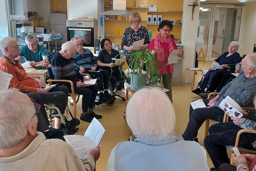 Gruppe von Senioren bei einer Veranstaltung mit einer Präsentation in einem Gemeinschaftsraum.