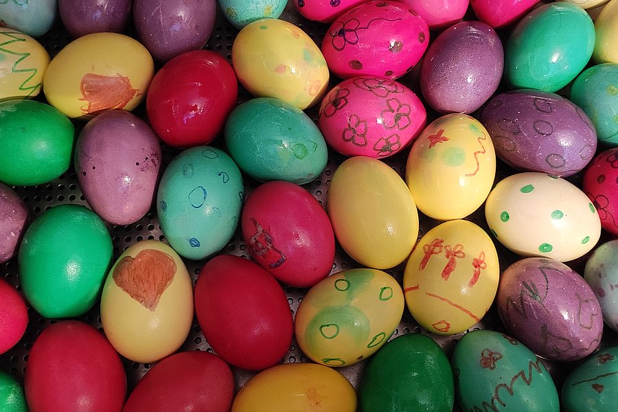 Bunte Ostereier in verschiedenen Farben mit handgemalten Verzierungen auf einem dekorativen Untergrund.