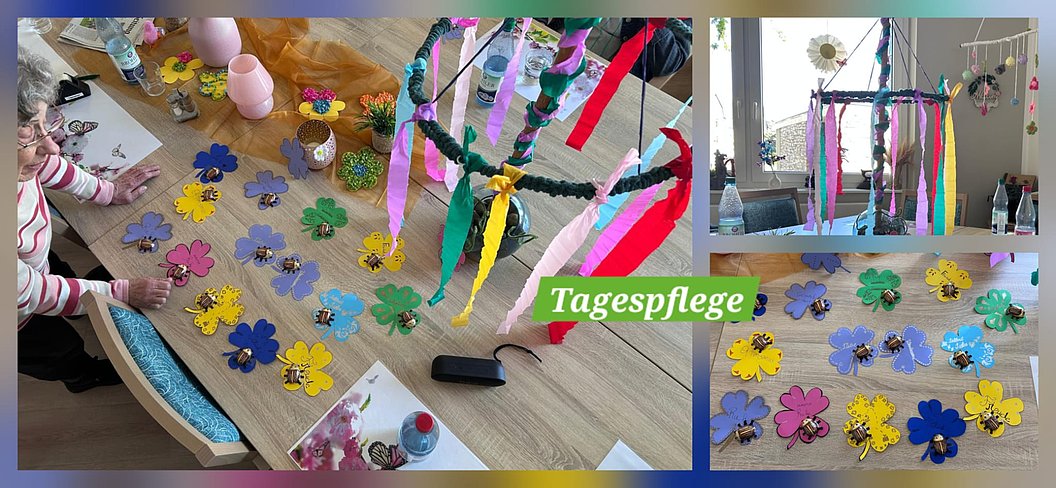 Kinder basteln bunte Papierblumen auf einem Holztisch und hängen bunte Bänder an eine grüne Girlande in einem hellen Raum