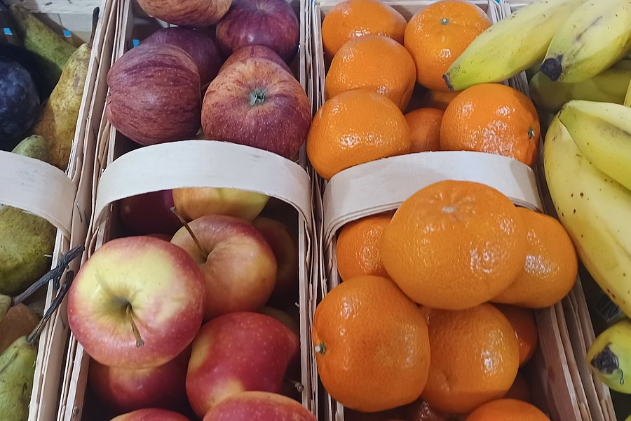 Frisches Obst in Körben: Äpfel, Mandarinen und Bananen auf einem Markt.