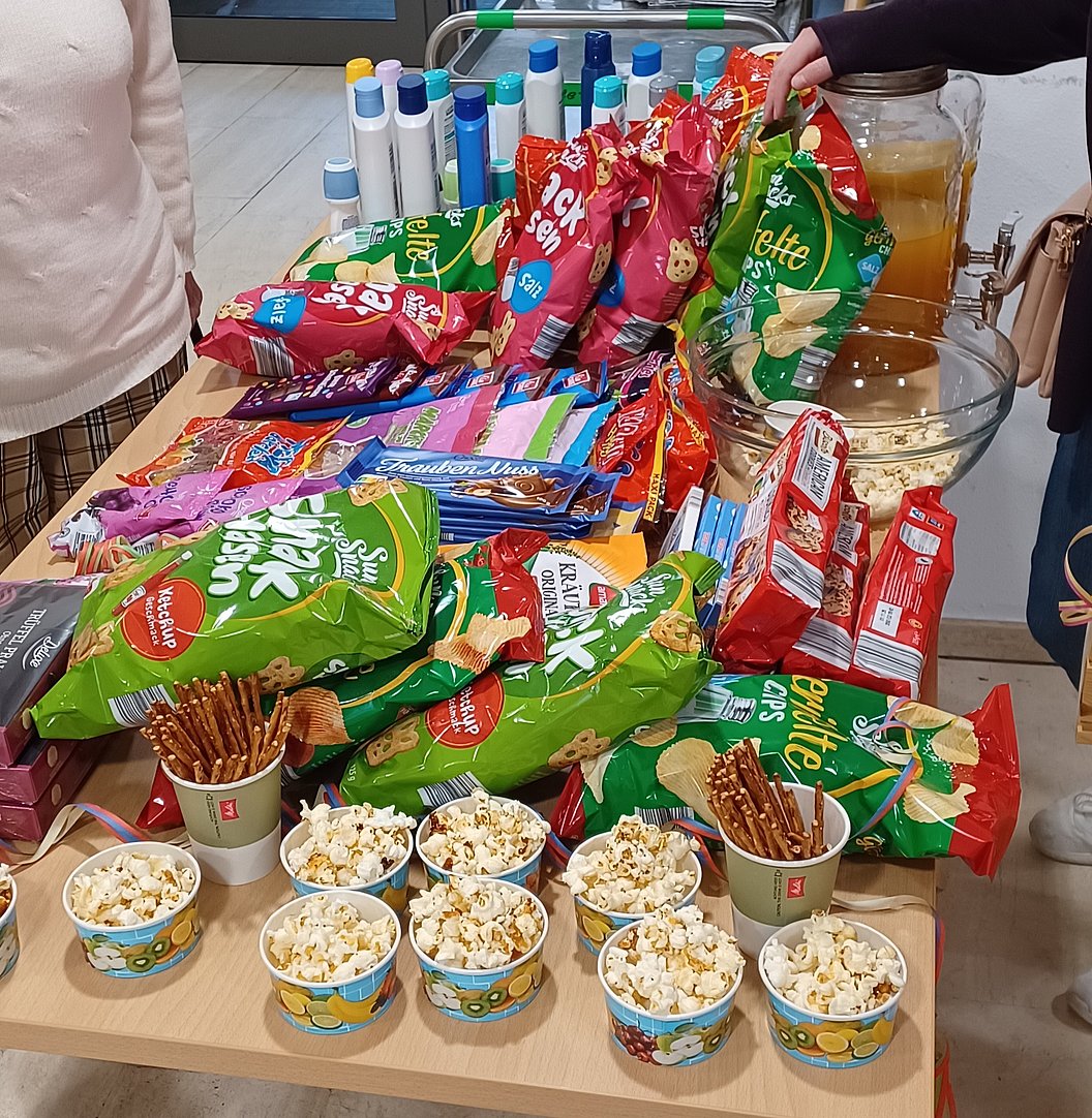 Tisch mit Snacks: Chips, Popcorn in Bechern und Getränken, bereit zum Genießen.