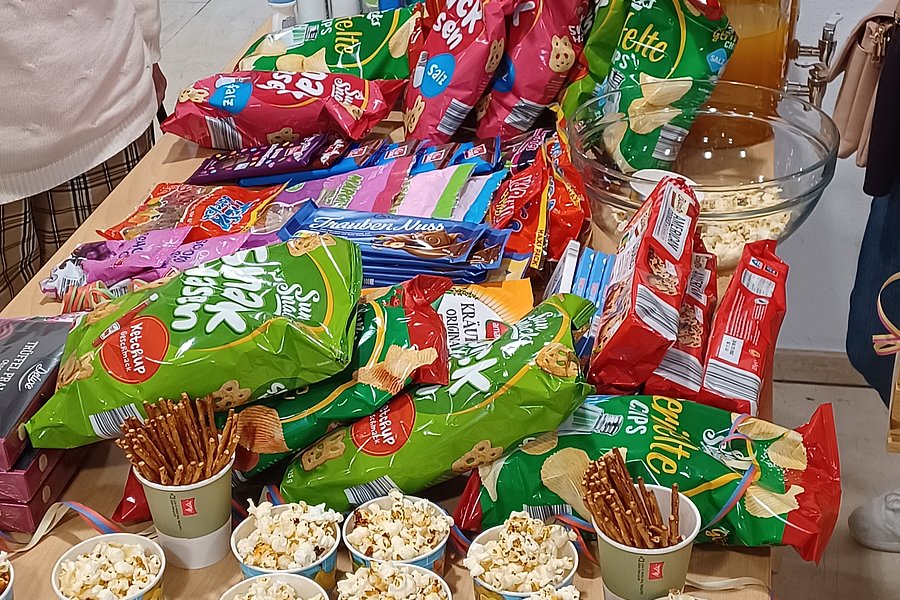 Tisch mit Snacks: Chips, Popcorn in Bechern und Getränken, bereit zum Genießen.